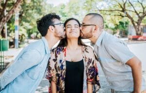 woman being kissed by two males