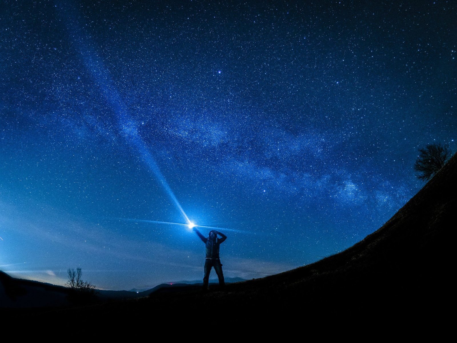 silhouette of man holding flashlight searching in the dark