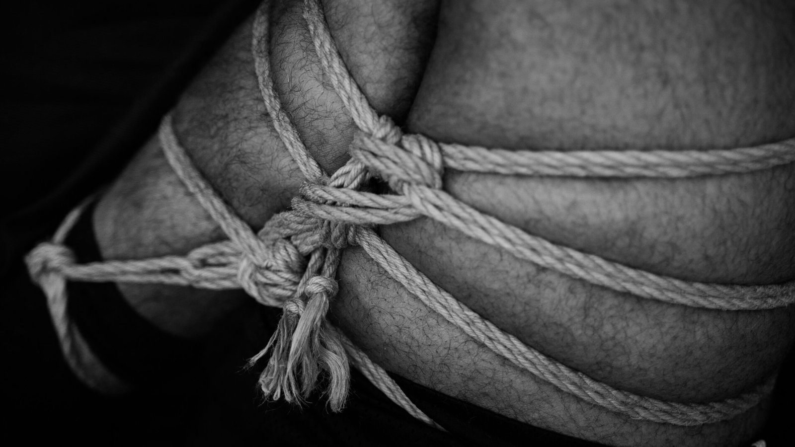 grayscale photo of rope tied on a leg