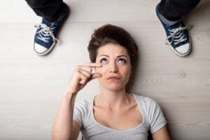 woman lying floor looking at man, gesturing a small penis