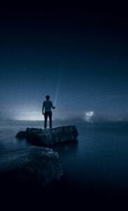 man standing alone on a rock with a torch